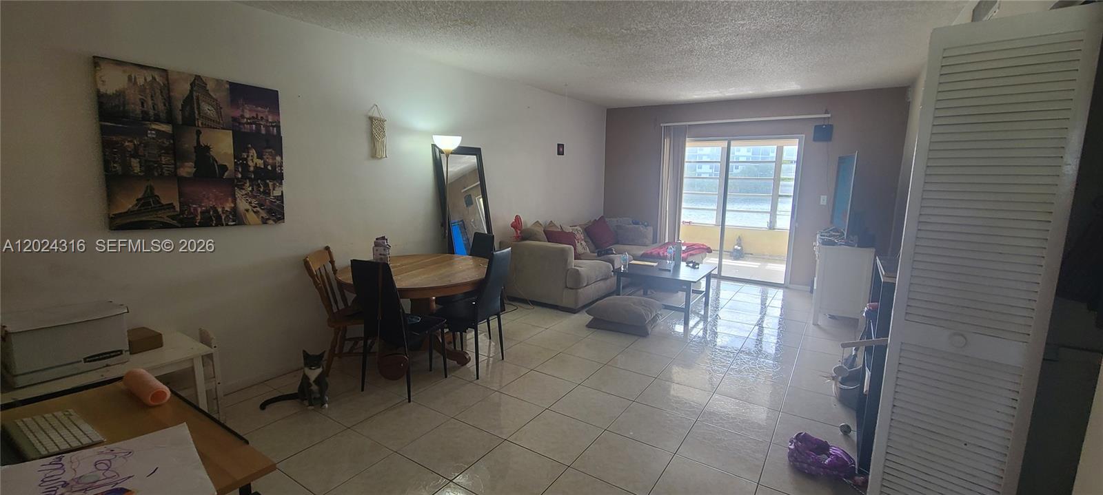 A living and dining area features tiled floors, a beige sofa, and a sliding glass door — 19305 NE 2nd Ave # 2323, Miami FL 33179, MIAMI, FL