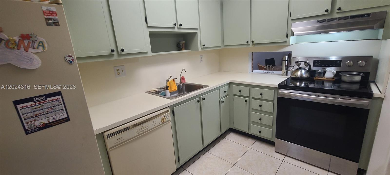 A kitchen features light green cabinets, white countertops, stainless steel appliances, and tiled flooring — 19305 NE 2nd Ave # 2323, Miami FL 33179, MIAMI, FL