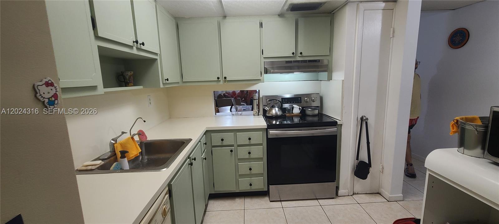 A kitchen features light green cabinets, white countertops, and a stainless steel stove — 19305 NE 2nd Ave # 2323, Miami FL 33179, MIAMI, FL