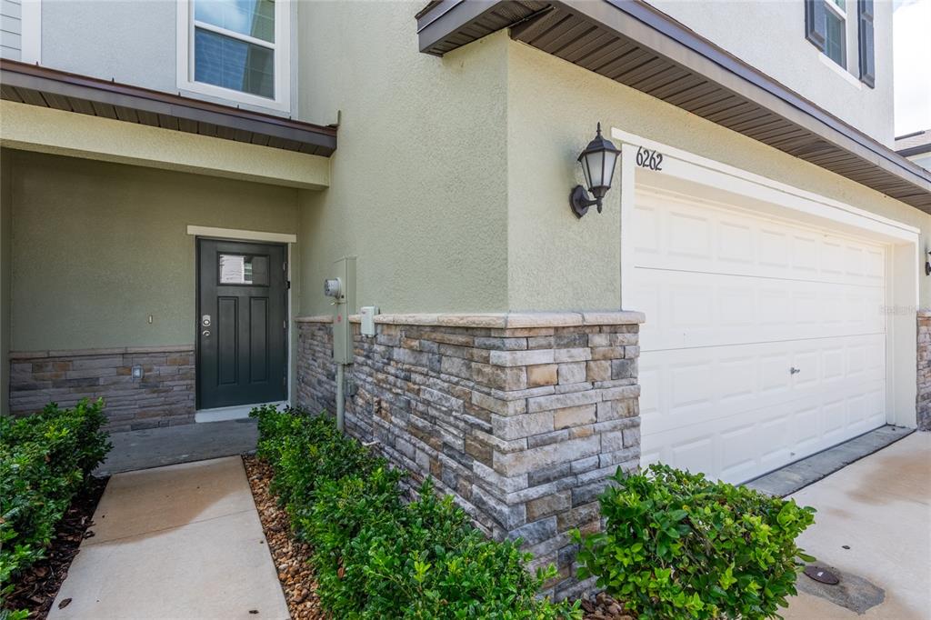 The exterior of a two-story home features a garage, stone veneer, and a front entrance — 6262 SHINER STREET, LAND O LAKES, FL