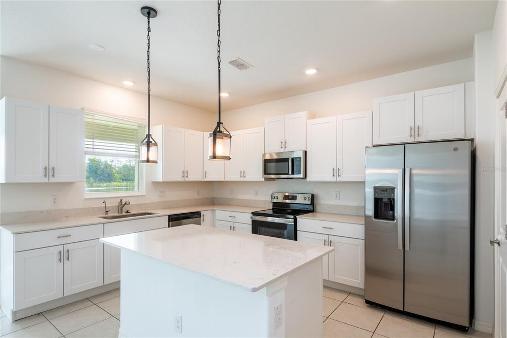 A kitchen with white cabinets, stainless steel appliances, a center island, and tile flooring — 6262 SHINER STREET, LAND O LAKES, FL