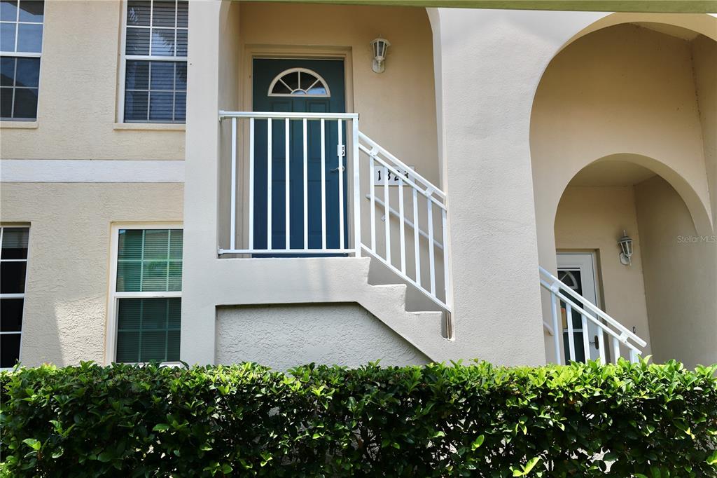 The exterior of a two-story residential building features a staircase leading to an upper entrance — 4275 CASTLEBRIDGE LANE UNIT 1323, SARASOTA, FL