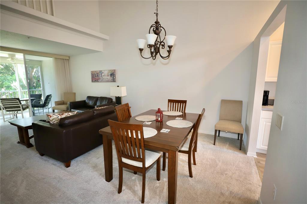 A dining area with a wooden table and chairs sits adjacent to a living room — 4275 CASTLEBRIDGE LANE UNIT 1323, SARASOTA, FL