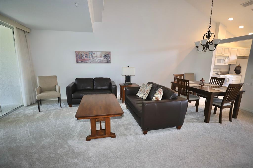 A living and dining area features dark leather furniture, a wooden coffee table, and carpeted floors — 4275 CASTLEBRIDGE LANE UNIT 1323, SARASOTA, FL