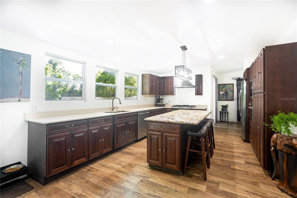 A kitchen features dark wood cabinets, granite countertops, a large island, and stainless steel appliances — 32316 CHIPOLA TRAIL, SORRENTO, FL