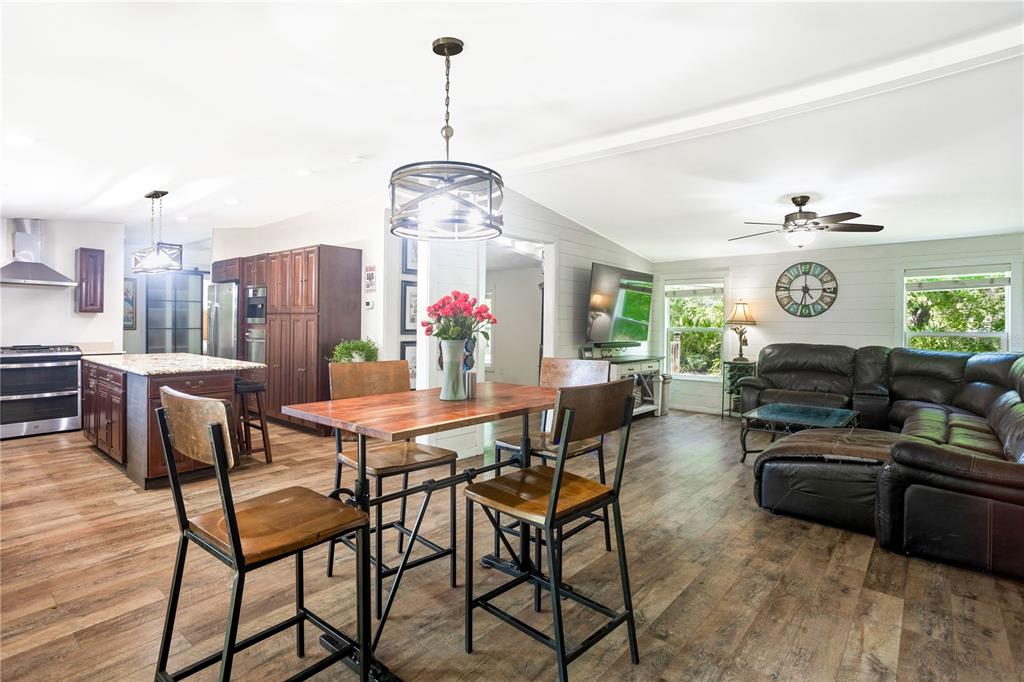 An open-concept kitchen, dining area, and living room feature wood-look flooring and dark cabinetry — 32316 CHIPOLA TRAIL, SORRENTO, FL