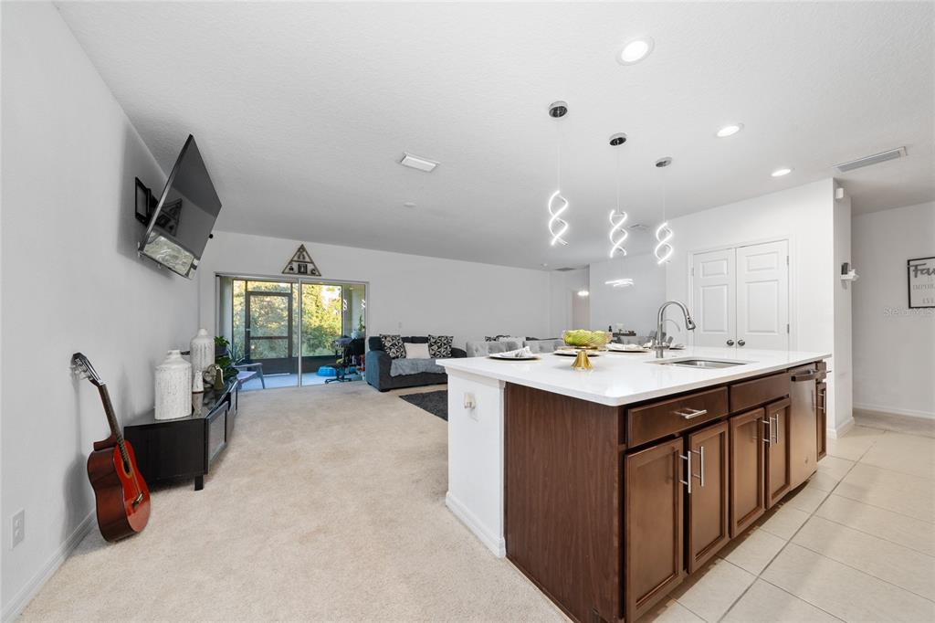 A kitchen with a large island and dark cabinets overlooks a carpeted living area — 669 JUPITER BEACH ROAD, GROVELAND, FL
