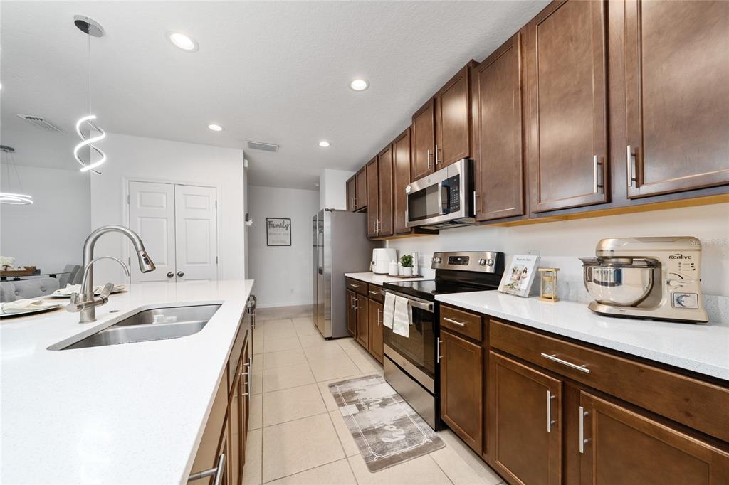 A kitchen features dark wood cabinets, white countertops, stainless steel appliances, and a central island — 669 JUPITER BEACH ROAD, GROVELAND, FL