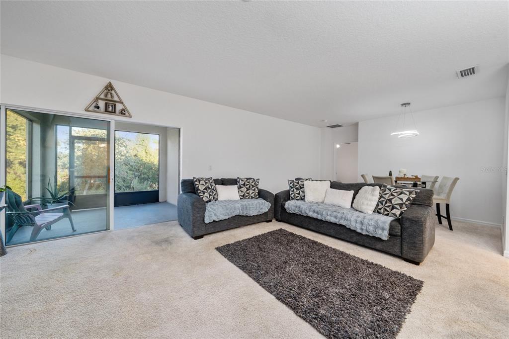 A living room with gray sofas, a dark rug, and a sliding door to a patio — 669 JUPITER BEACH ROAD, GROVELAND, FL