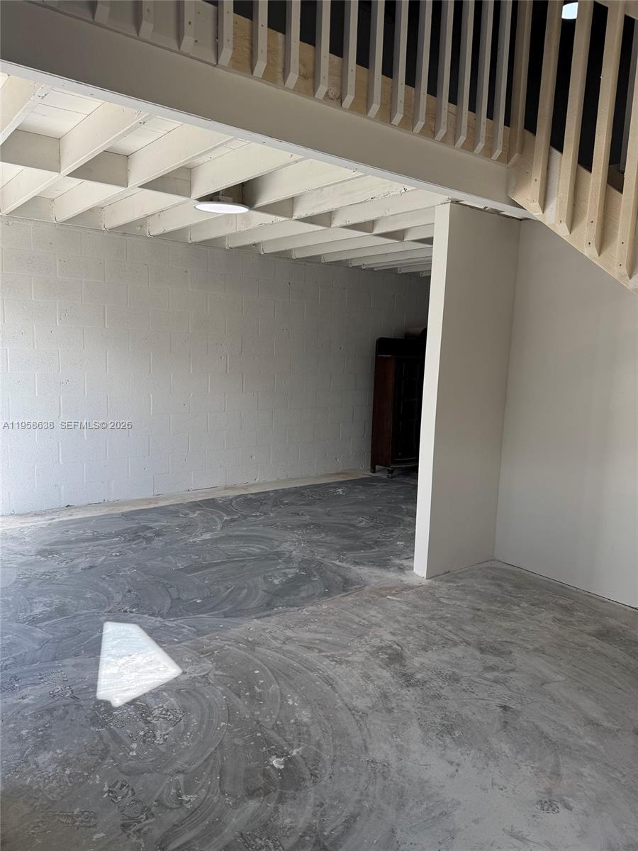An unfinished room features exposed ceiling joists, a concrete floor, and a wooden staircase — 12290 SW 131st Ave # 14, Miami FL 33186, MIAMI, FL