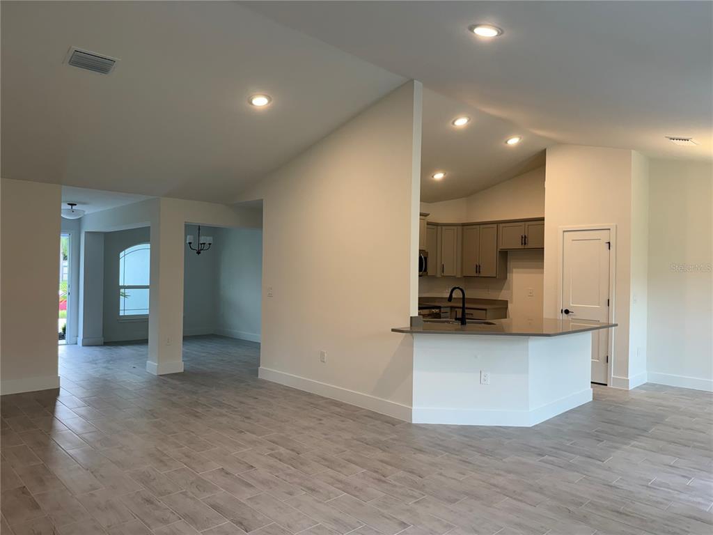 A kitchen with gray cabinets and a breakfast bar overlooks an open-concept living area — 2724 NELLIE LANE, NORTH PORT, FL