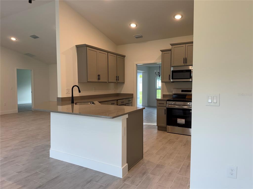 A kitchen features gray cabinets, stainless steel appliances, and a peninsula with a sink — 2724 NELLIE LANE, NORTH PORT, FL