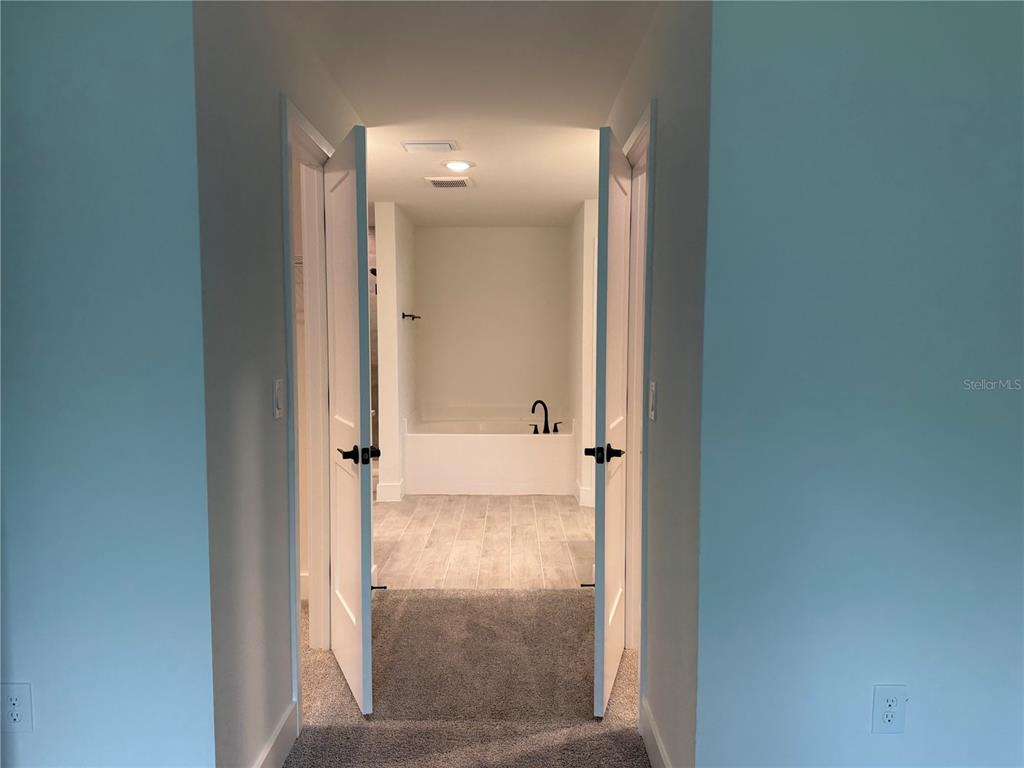 A doorway with open doors leads from a carpeted room into a tiled bathroom — 2724 NELLIE LANE, NORTH PORT, FL