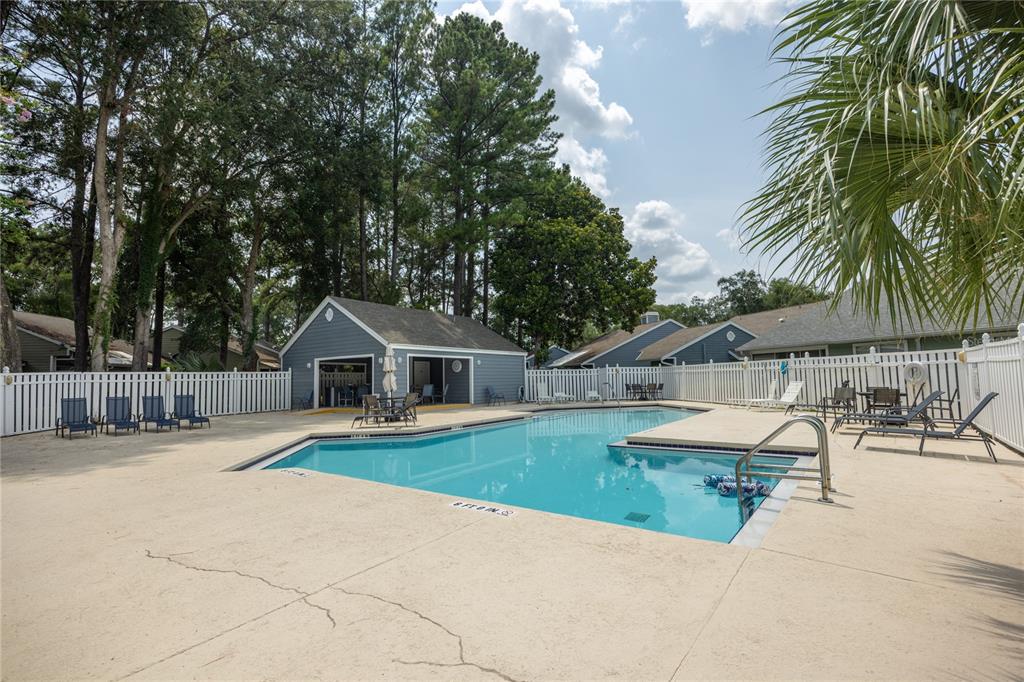 An outdoor swimming pool surrounded by a concrete deck, white fencing, and a small building — 1013 NW 124TH DRIVE, NEWBERRY, FL