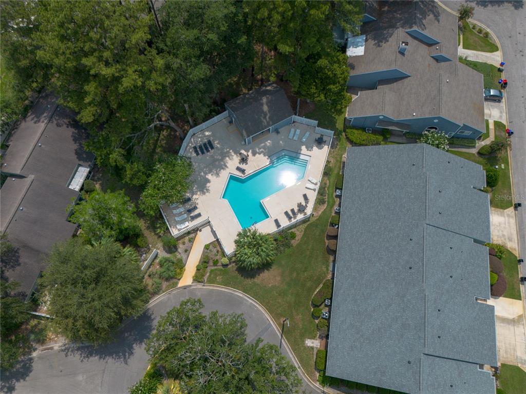 An aerial view shows a swimming pool with a deck and surrounding apartment buildings — 1013 NW 124TH DRIVE, NEWBERRY, FL
