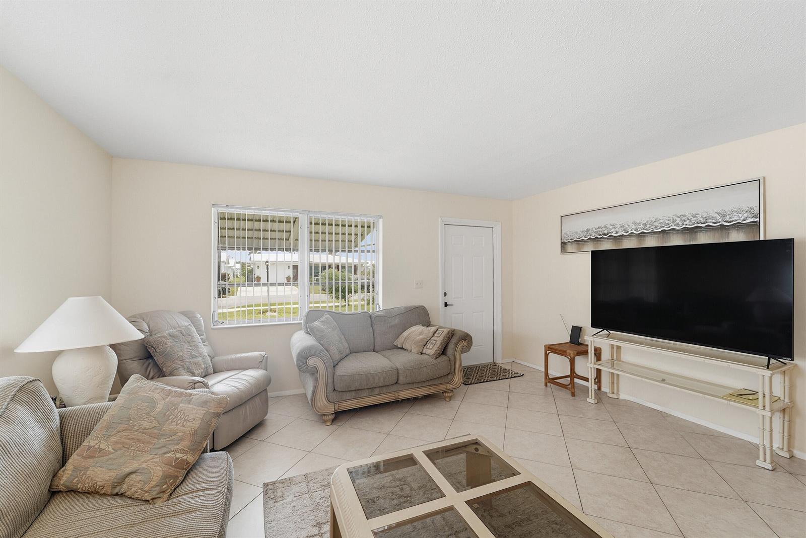 A living room features tile flooring, a television on a stand, and two sofas — 220 Leisure Boulevard, Pompano Beach FL 33064, POMPANO BEACH, FL