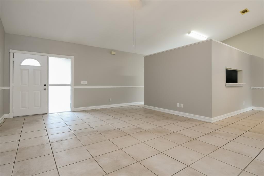 An empty room with light-colored tile flooring, gray walls, and a white front door — 1961 MARTINA STREET, APOPKA, FL