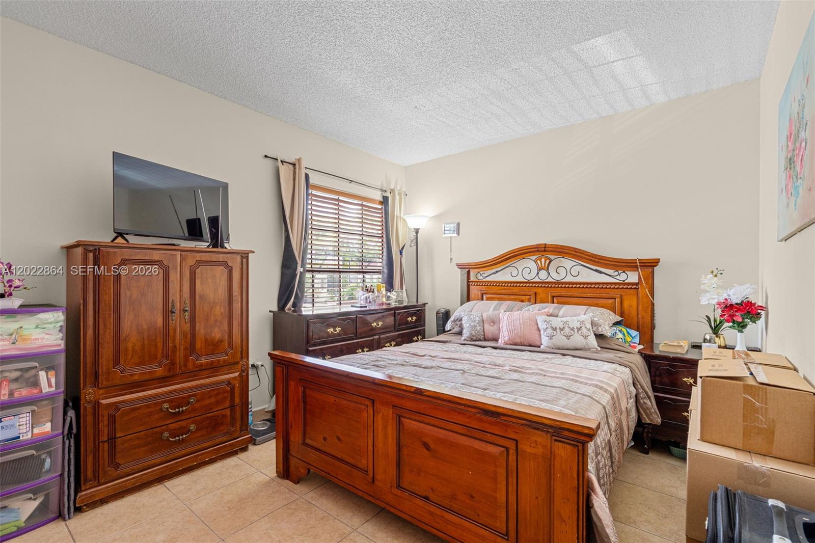 A bedroom features a wooden bed frame, a matching armoire, and tile flooring — 12927 SW 88th Ln # A205, Miami FL 33186, MIAMI, FL