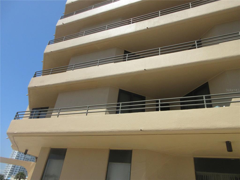 A low-angle view of a multi-story beige building with balconies and metal railings — 3023 S ATLANTIC AVENUE UNIT 2070, DAYTONA BEACH, FL