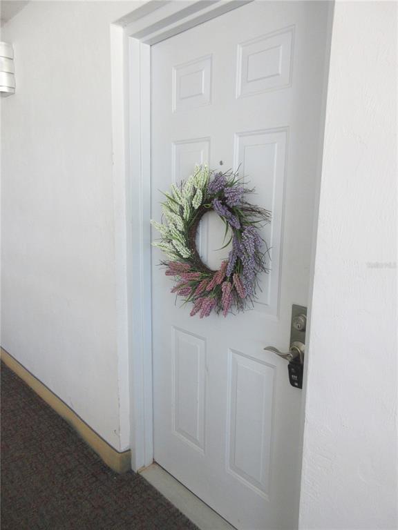A white door with a lavender wreath hangs in a hallway with carpeted flooring — 3023 S ATLANTIC AVENUE UNIT 2070, DAYTONA BEACH, FL
