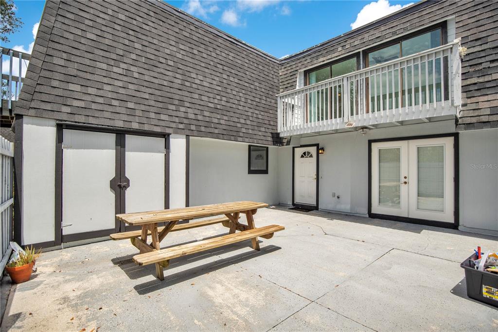 A concrete patio features a wooden picnic table in front of a two-story house exterior — 2577 DERBYSHIRE CIRCLE, CASSELBERRY, FL