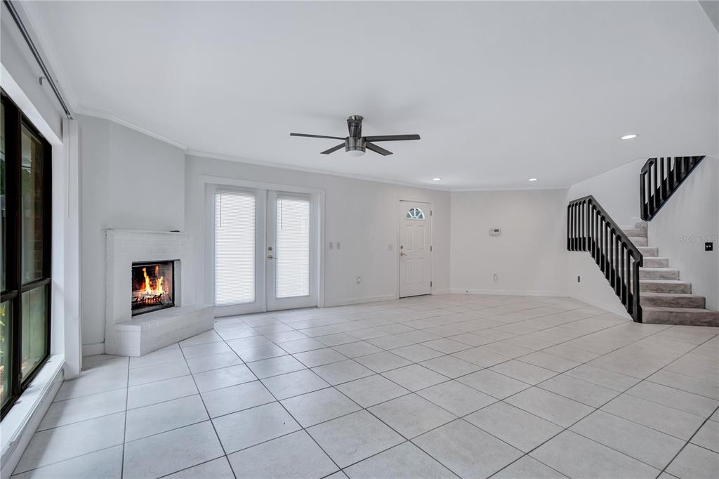 A living room features white tile floors, a fireplace, a staircase, and glass doors — 2577 DERBYSHIRE CIRCLE, CASSELBERRY, FL