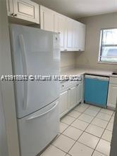 A kitchen features white cabinets, a white refrigerator, and a blue dishwasher on tiled floors — 1316 White Pine Dr, Wellington FL 33414, WELLINGTON, FL
