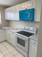 A kitchen features white cabinets, a white electric range, and a blue-wrapped over-the-range microwave — 1316 White Pine Dr, Wellington FL 33414, WELLINGTON, FL