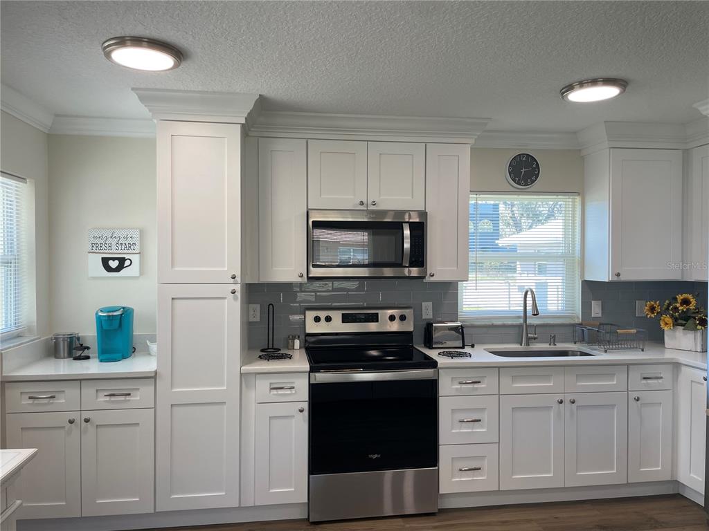 A kitchen features white cabinetry, stainless steel appliances, a gray subway tile backsplash, and countertops — 16931 FRANKLIN AVENUE, MONTVERDE, FL