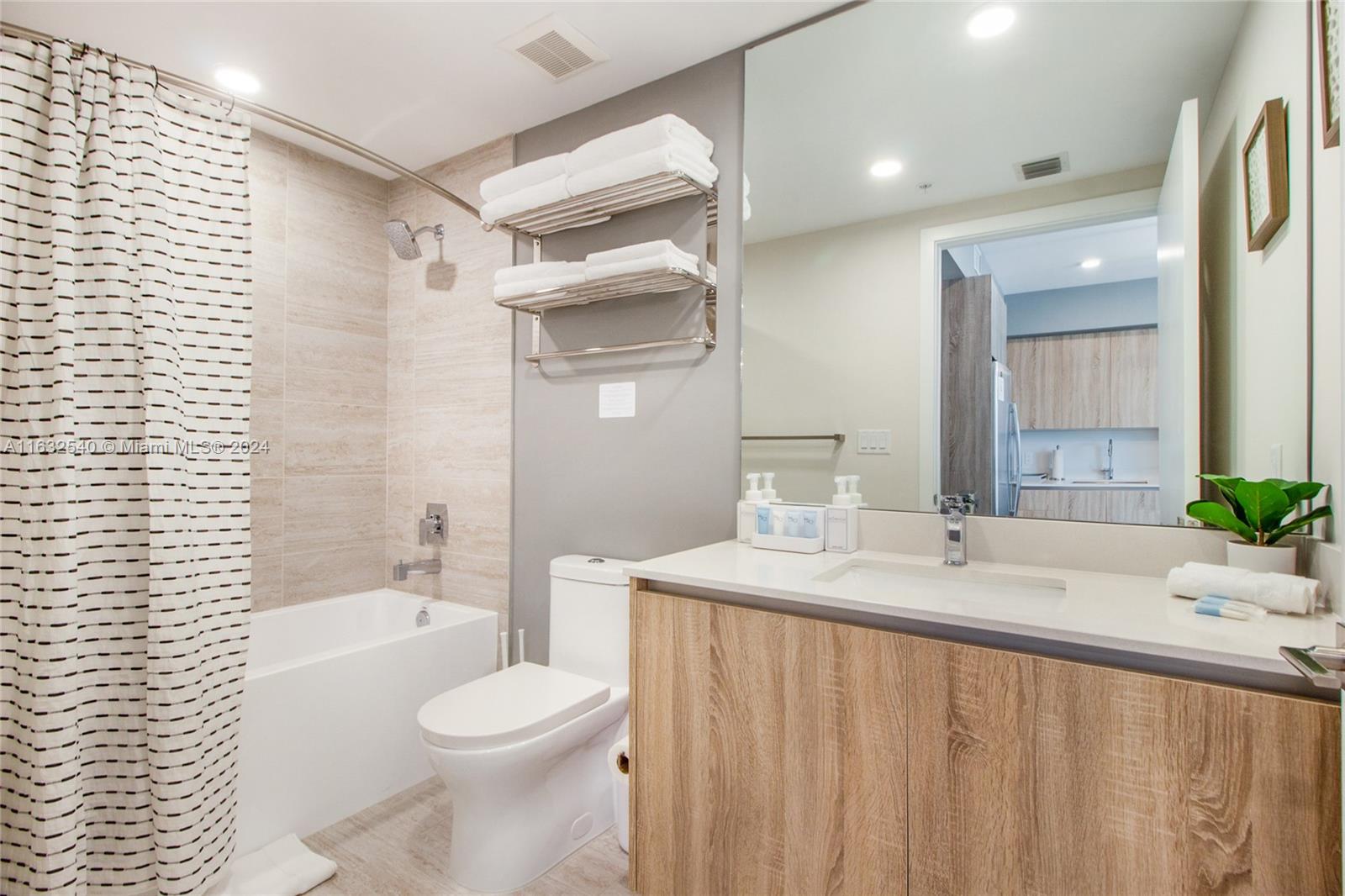 A modern bathroom features a bathtub with a shower, a toilet, and a wood-toned vanity — 3900 Biscayne Blvd # 917, Miami FL 33137, MIAMI, FL