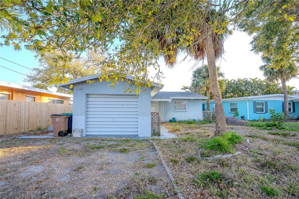 A single-story house with a grey garage and exterior, surrounded by trees and sparse landscaping — 407 20TH AVENUE, INDIAN ROCKS BEACH, FL