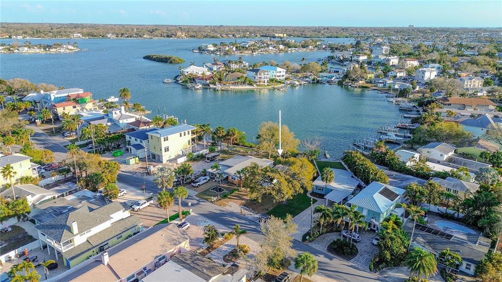 An aerial view shows a waterfront residential property with a white arrow pointing toward a house — 407 20TH AVENUE, INDIAN ROCKS BEACH, FL