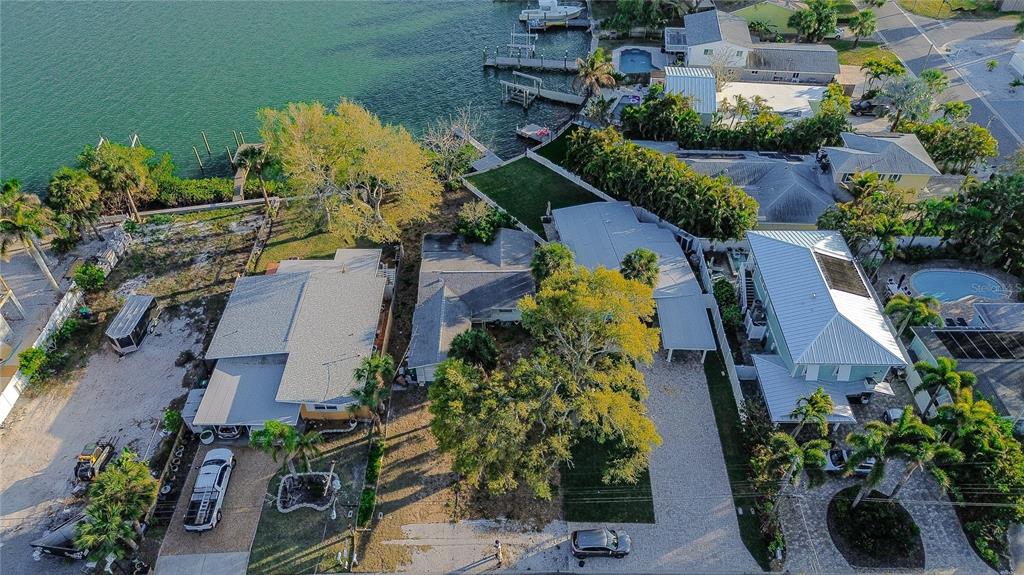 An aerial view shows three houses with driveways and trees situated along a waterfront — 407 20TH AVENUE, INDIAN ROCKS BEACH, FL