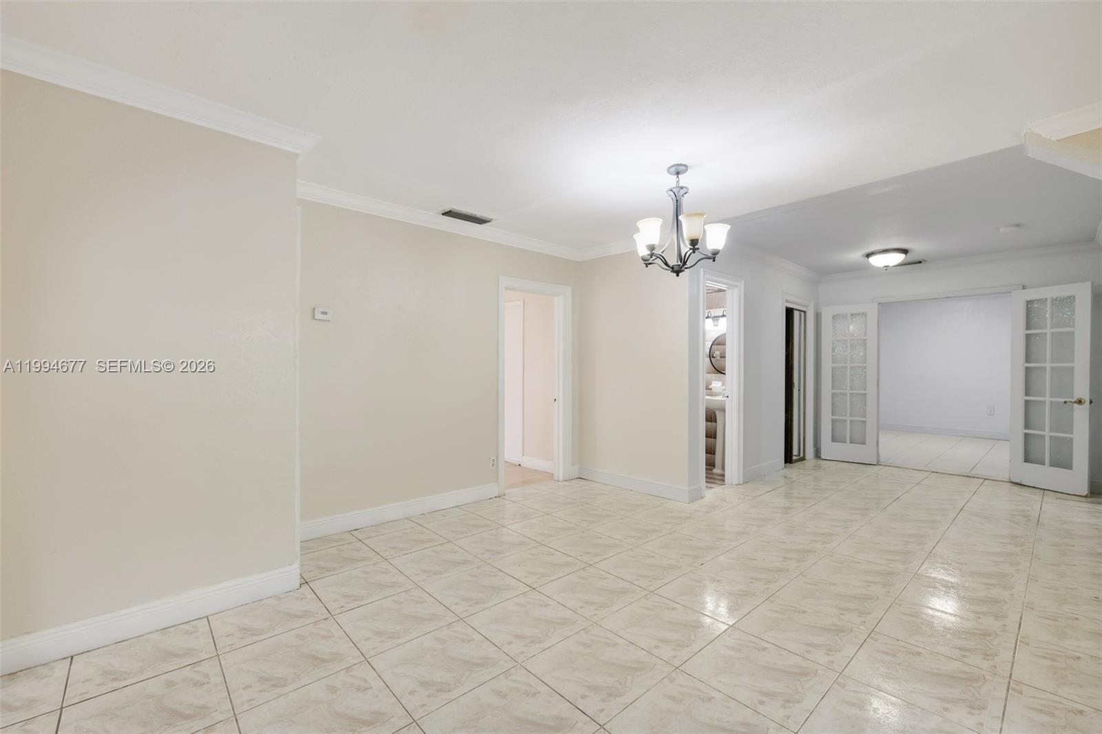 A tiled room features a chandelier, white walls, and French doors leading to another space — 674 W 23rd St, Hialeah FL 33010, HIALEAH, FL