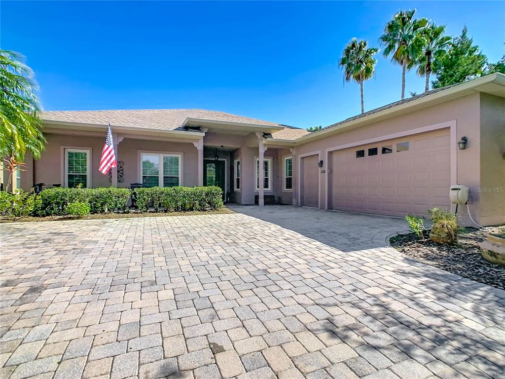 A single-story house with a paved driveway, a two-car garage, and an American flag — 1155 N GLENDORA ROAD, KISSIMMEE, FL