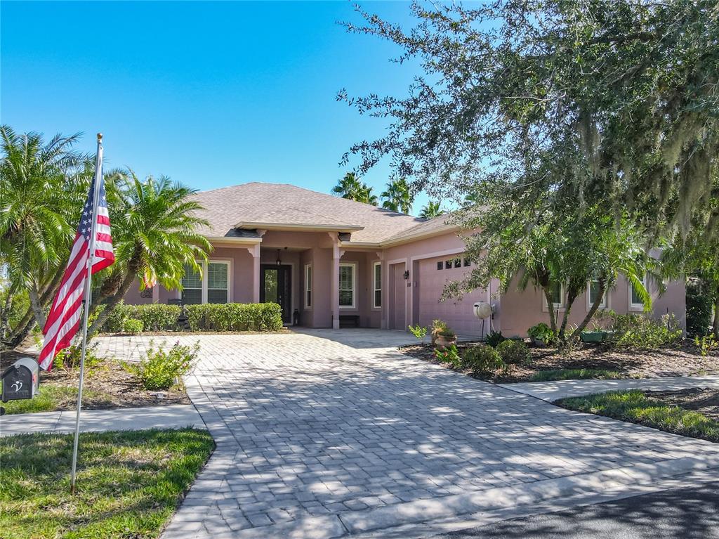 A single-story house with a paved driveway, palm trees, and an American flag in front — 1155 N GLENDORA ROAD, KISSIMMEE, FL