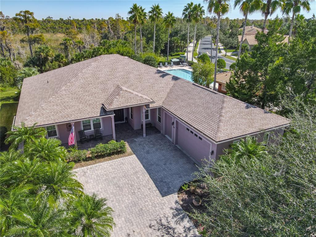 An aerial view of a pink house with a paved driveway and a backyard pool — 1155 N GLENDORA ROAD, KISSIMMEE, FL