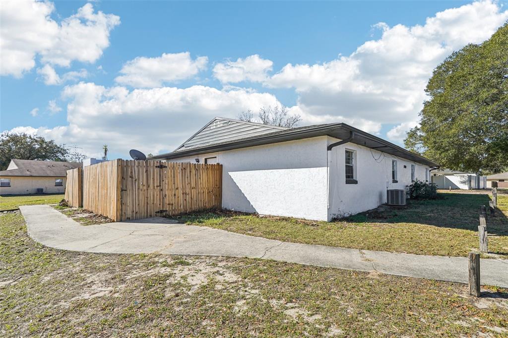 A white stucco house with a wooden fence and a concrete walkway on a lawn — 5080 SE 31ST STREET, OCALA, FL