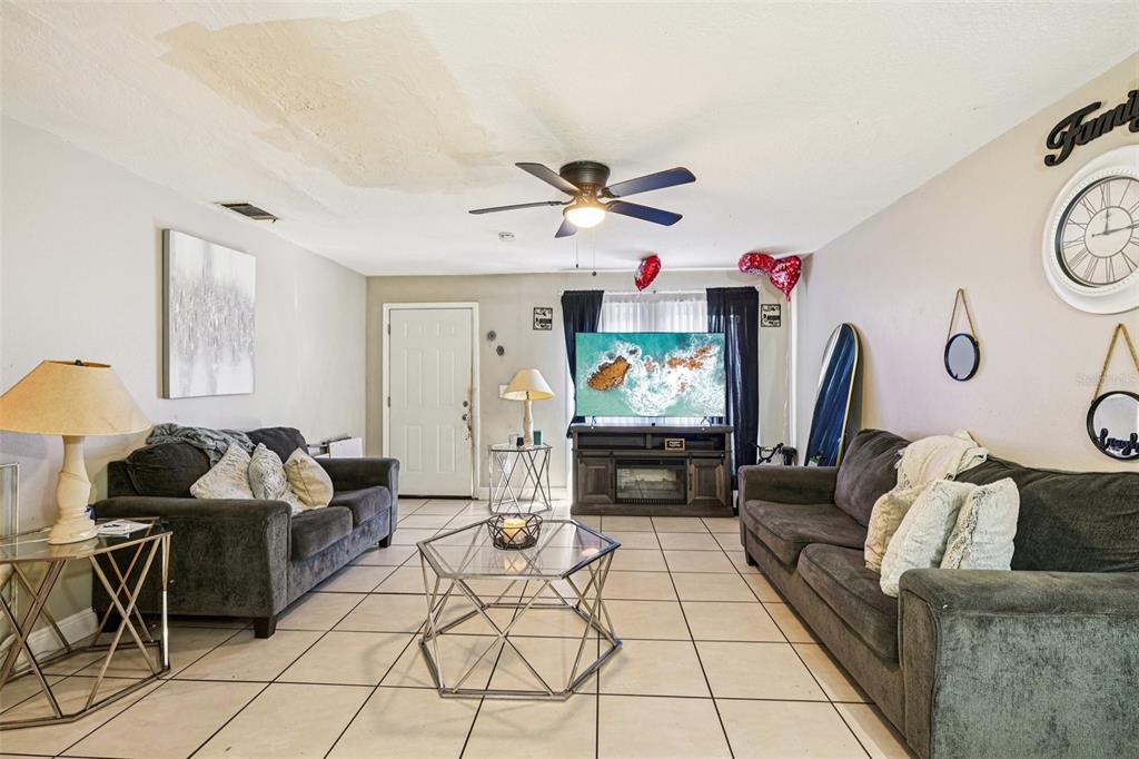 A living room features two dark sofas, a glass coffee table, and tile flooring — 5080 SE 31ST STREET, OCALA, FL