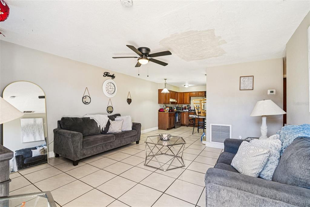 A living room with tile floors, two gray sofas, and an open kitchen in back — 5080 SE 31ST STREET, OCALA, FL