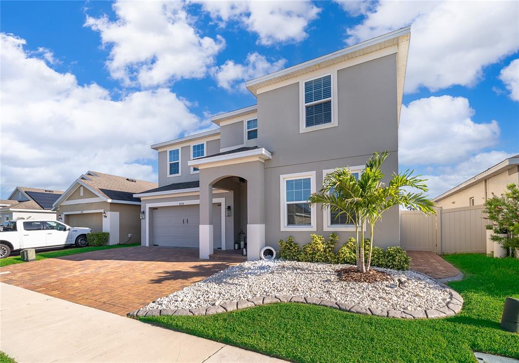 A two-story gray house with a paver driveway, a garage, and a small palm tree — 4724 MARCOS CIRCLE, KISSIMMEE, FL
