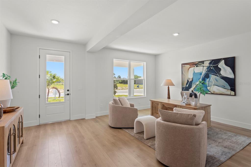 A bright home office features light wood floors, two beige armchairs, and a wooden desk — 7770 OCEAN SPRAY TRAIL, PALMETTO, FL