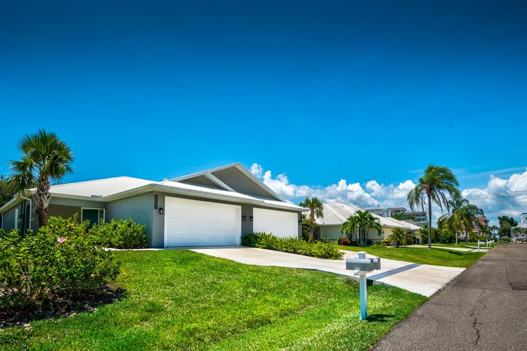 A gray duplex house with two garage doors and a lawn under a blue sky — 215 LEWIS CIRCLE UNIT 111, PUNTA GORDA, FL