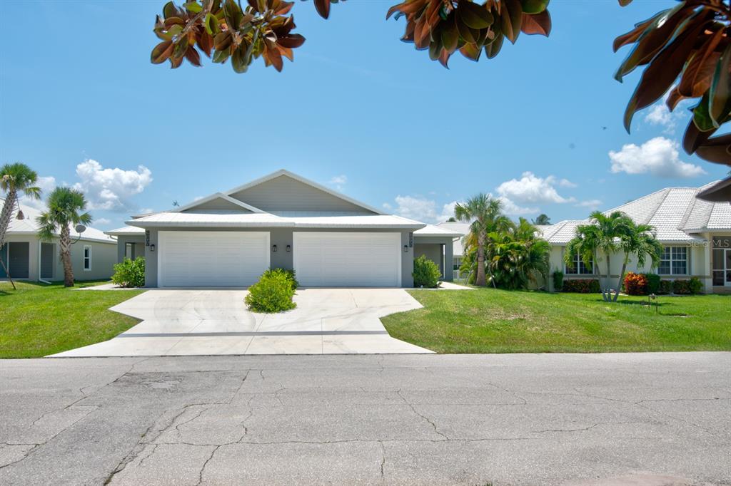 A duplex house with two white garage doors and a concrete driveway under a blue sky — 215 LEWIS CIRCLE UNIT 111, PUNTA GORDA, FL