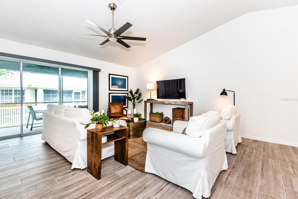 A living room features white slipcovered furniture, a wood console table, and tile flooring — 215 LEWIS CIRCLE UNIT 111, PUNTA GORDA, FL