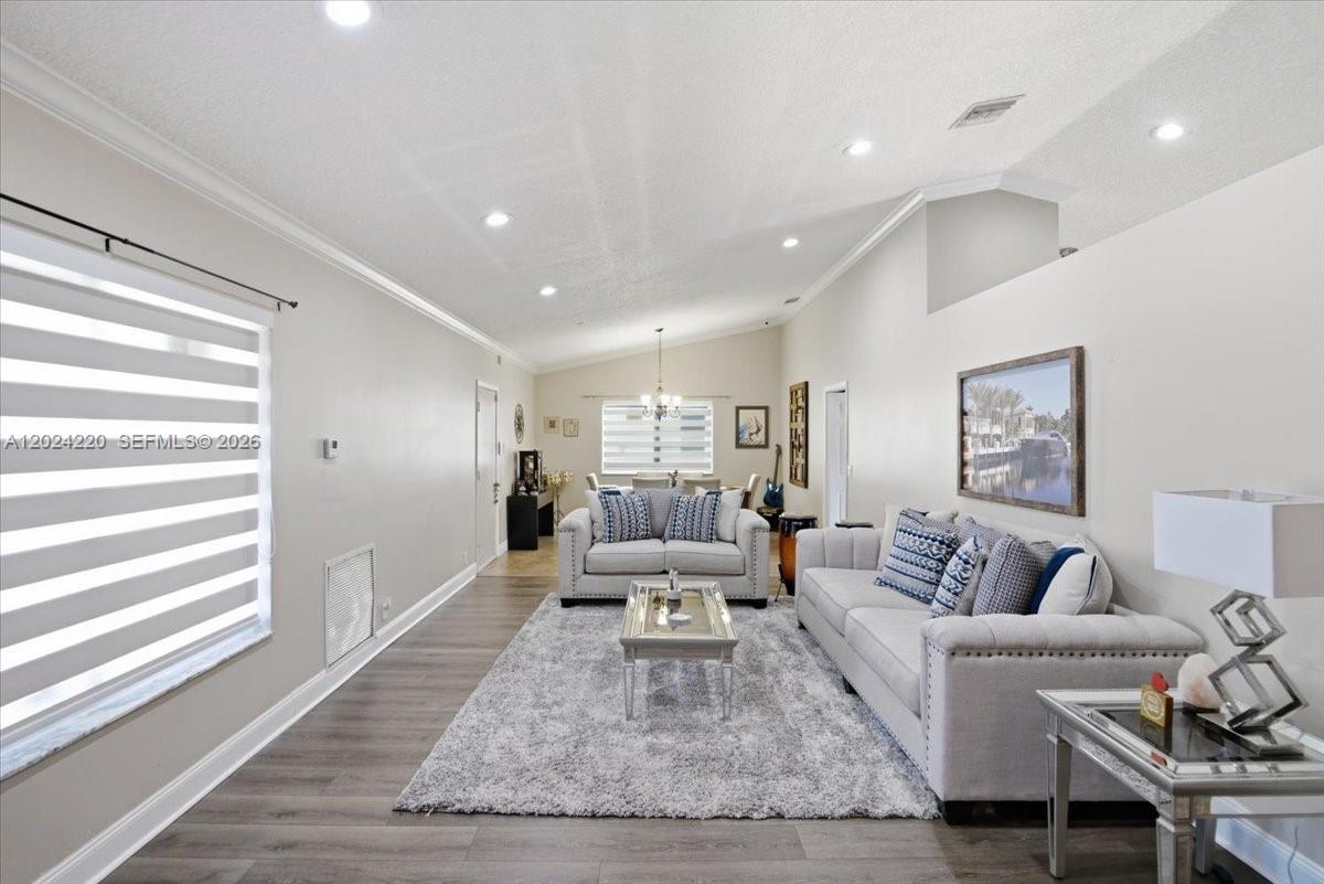 A living room features light gray walls, wood-look flooring, a shag rug, and vaulted ceilings — 6520 Olde Moat Way, Davie FL 33331, DAVIE, FL