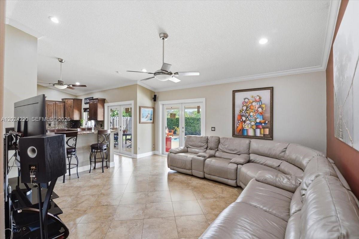 A living room features a large sectional sofa, tile flooring, and a kitchen breakfast bar — 6520 Olde Moat Way, Davie FL 33331, DAVIE, FL
