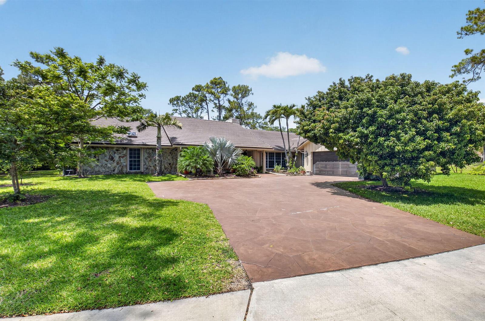 A single-story house with a stone facade, brown tile roof, and a large paved driveway — 7332 Estrella Court, Boca Raton FL 33433, BOCA RATON, FL
