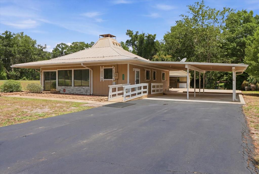 A single-story house with a metal roof, carport, and wheelchair ramp on a paved driveway — 5383 N CARL G ROSE HIGHWAY, HERNANDO, FL