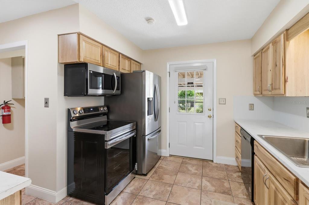 A kitchen features light wood cabinets, stainless steel appliances, a tile floor, and a back door — 5383 N CARL G ROSE HIGHWAY, HERNANDO, FL